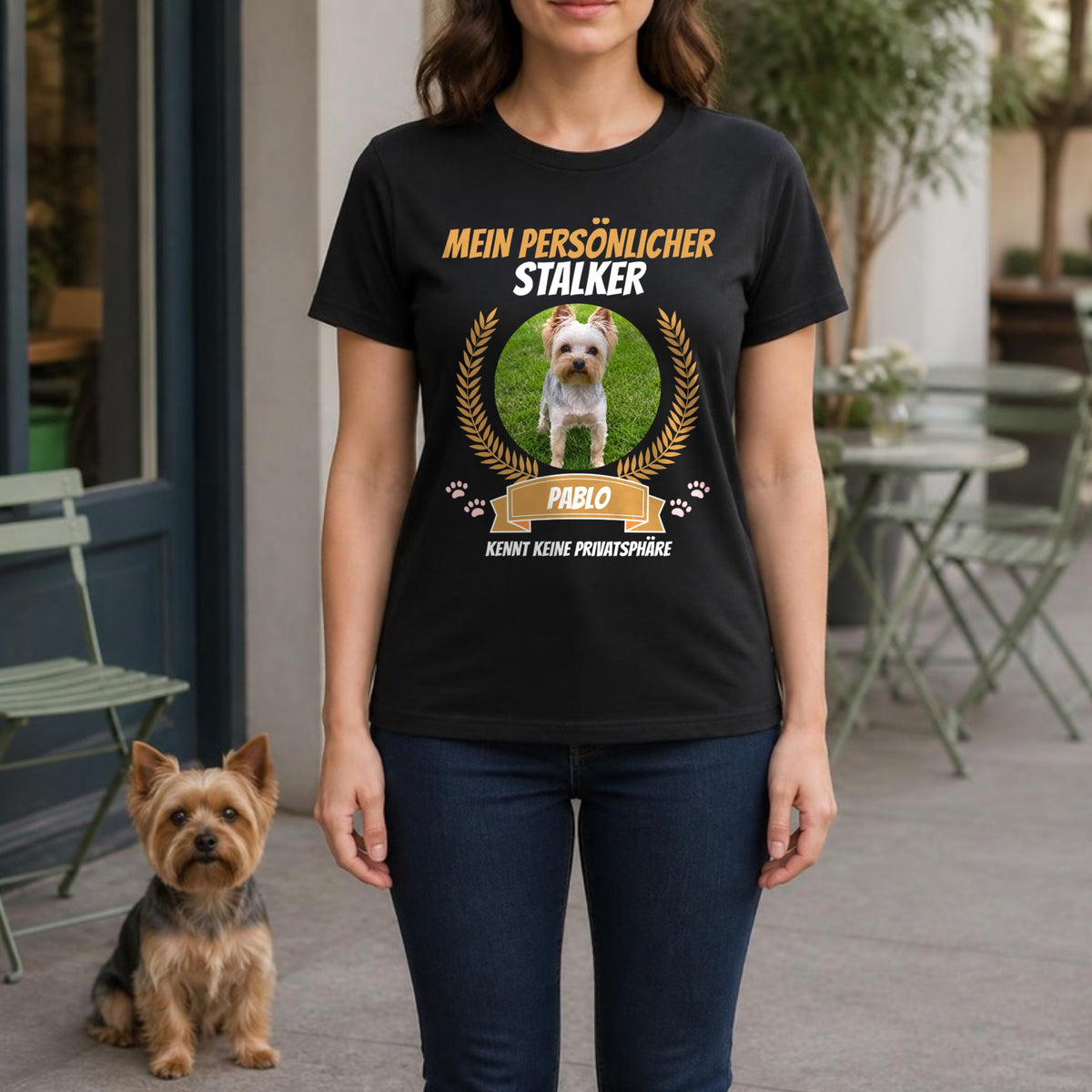 Frau im schwarzen T-Shirt 'Mein persoenlicher Stalker kennt keine Privatsphaere' mit Medaillon-Foto, Yorkshire Terrier sitzt daneben – personalisiertes Hunde-T-Shirt mit Foto und Name | Lil Snouts