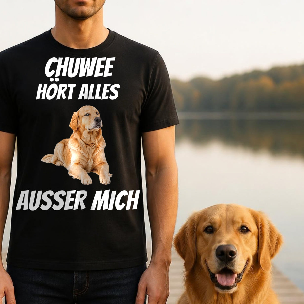 Mann traegt schwarzes T-Shirt Hoert alles ausser mich mit Golden Retriever am Seeufer